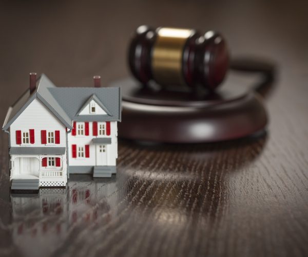 Gavel and Small Model House on Wooden Table.