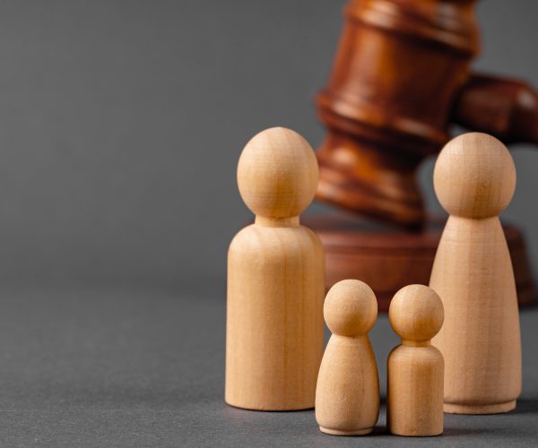 Wooden toy family and judge mallet close up. Family divorce concept